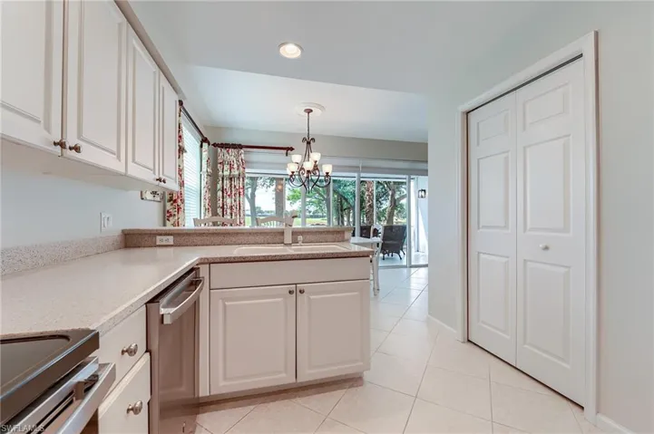 Kitchen featuring decorative light fixtures, a notable chandelier, white cabinets, and a sink