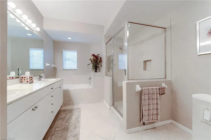 Full bathroom featuring tile patterned flooring, a sink, a stall shower, double vanity, and a bath