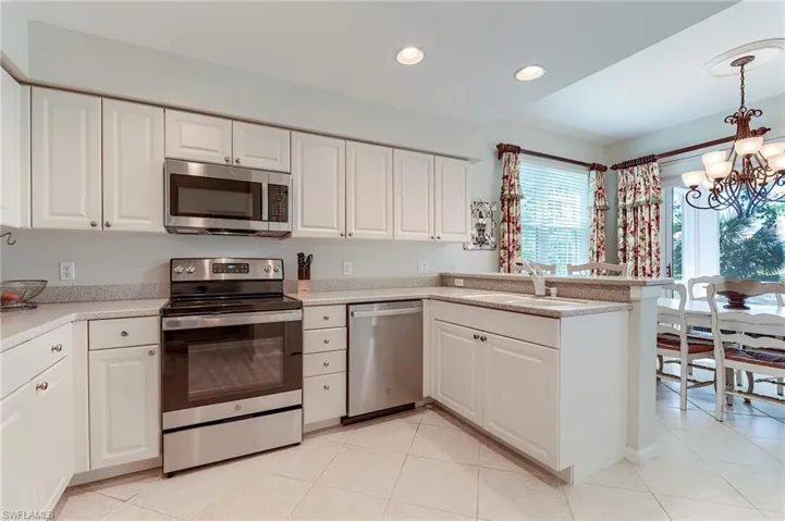Kitchen with light countertops, an inviting chandelier, a sink, white cabinets, and appliances with stainless steel finishes