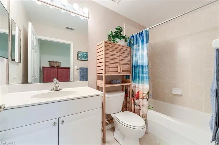 Full bath with tile patterned floors, toilet, vanity, shower / bath combo with shower curtain