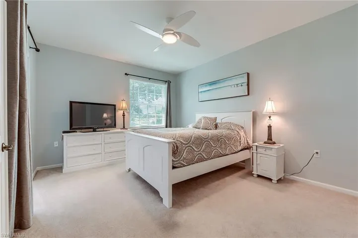 Bedroom featuring baseboards, a ceiling fan, and light colored carpet