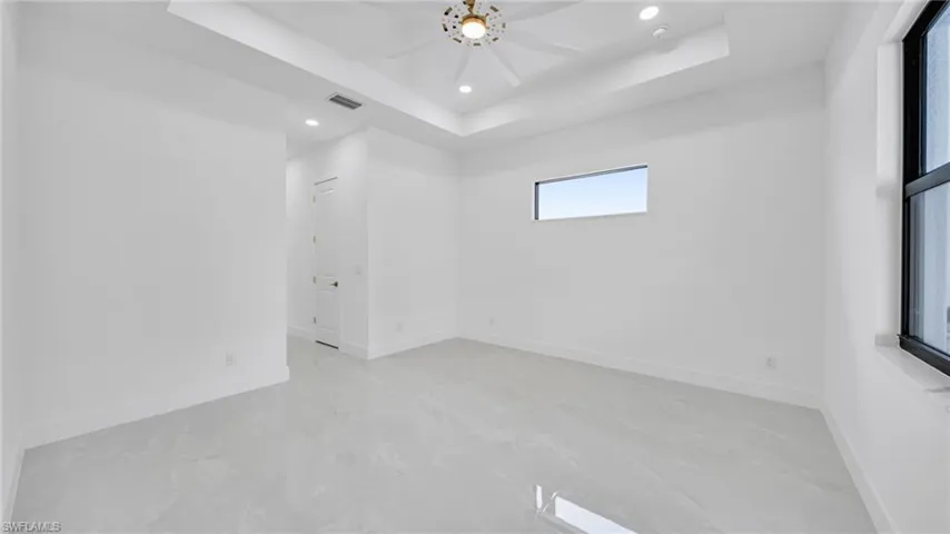 Unfurnished room featuring a tray ceiling, recessed lighting, and a ceiling fan