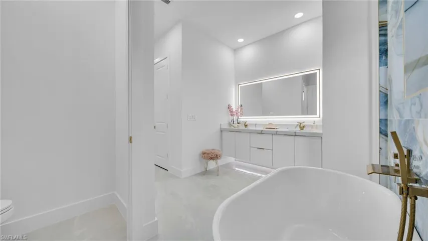 Bathroom with a freestanding tub, double vanity, and recessed lighting
