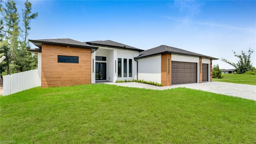 View of front of property with decorative driveway, an attached garage, and stucco siding