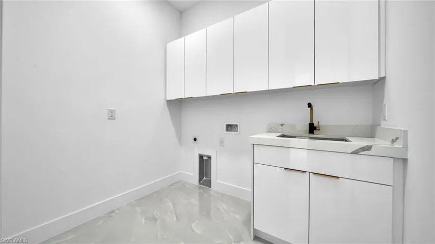 Laundry area featuring hookup for a washing machine, hookup for an electric dryer, cabinet space, and light marble finish flooring