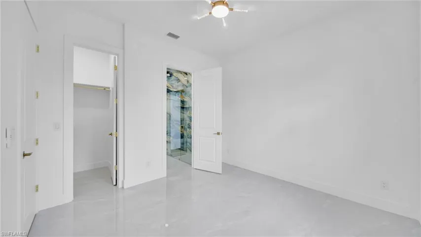 Unfurnished bedroom with a spacious closet and ceiling fan
