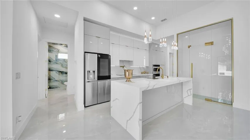 Kitchen with modern cabinets, stainless steel fridge with ice dispenser, white cabinets, pendant lighting, and light marble finish floors