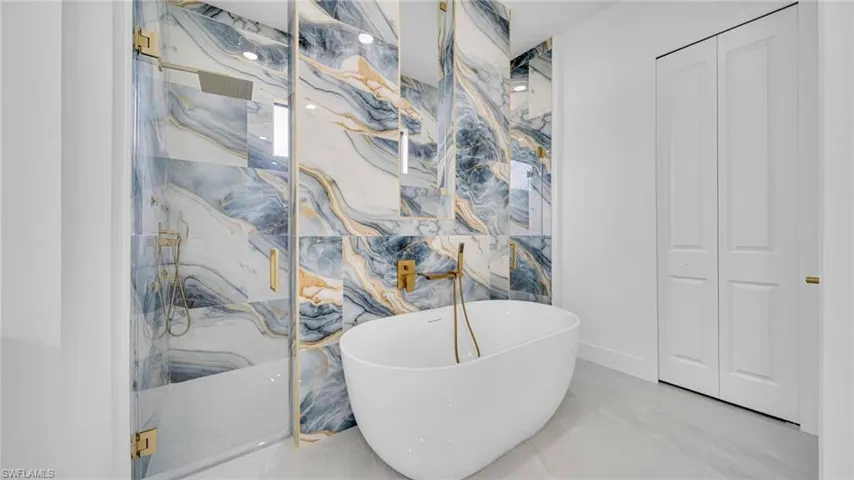 Full bathroom with a marble finish shower, a closet, a freestanding bath, and marble tiled flooring