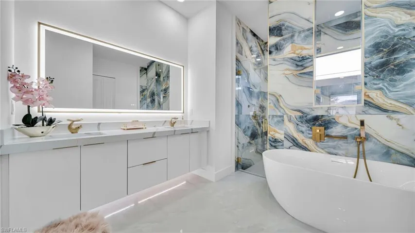 Bathroom featuring double vanity, a freestanding bath, and marble tiled floors