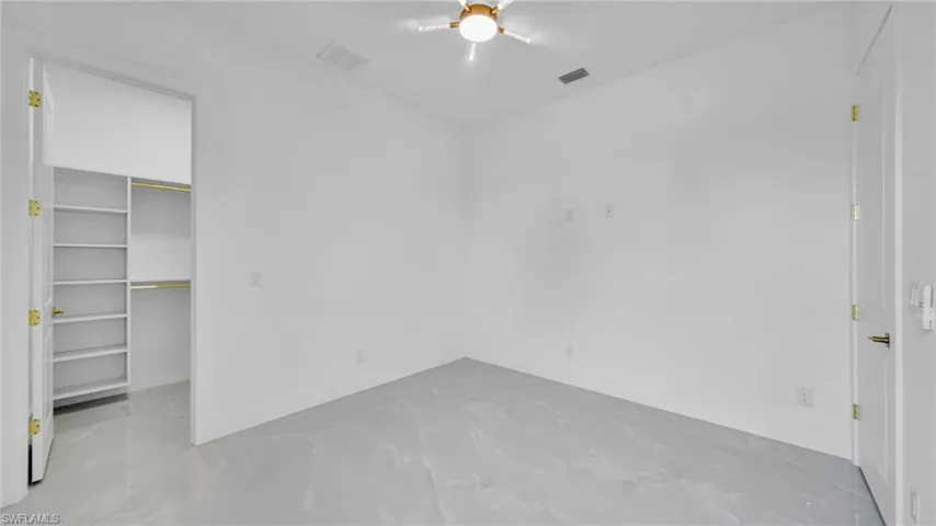 Unfurnished bedroom featuring a spacious closet and ceiling fan