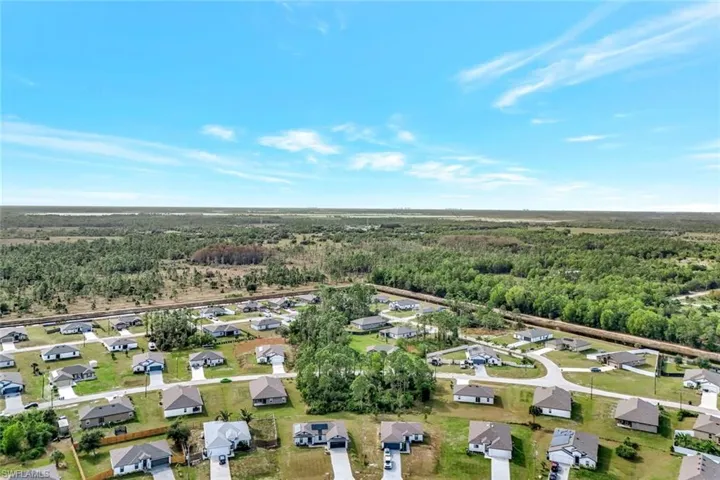 Aerial view of property's location with nearby suburban area and a forest