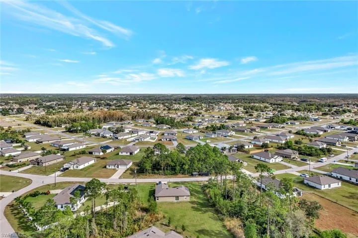 Aerial overview of property's location featuring nearby suburban area and a tree filled landscape
