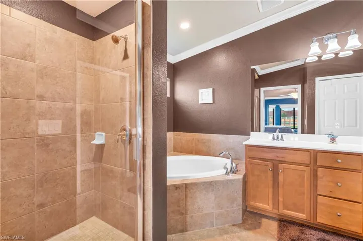 Primary bathroom with independent shower and bath, vanity, tile patterned flooring, and ornamental molding