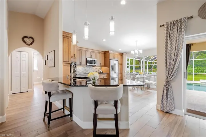 Kitchen featuring appliances with stainless steel finishes, a breakfast bar area, an inviting chandelier, pendant lighting, and backsplash