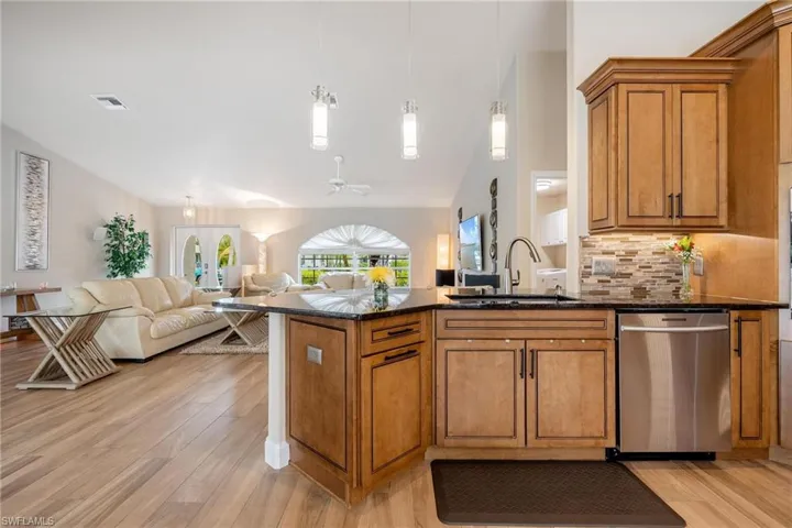 Kitchen with light plank tile flooring, dark stone counters, and backsplash.