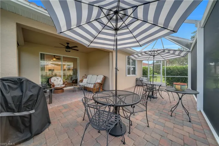View of patio / terrace featuring grilling area, a sunroom, outdoor dining area, a ceiling fan, and glass enclosure