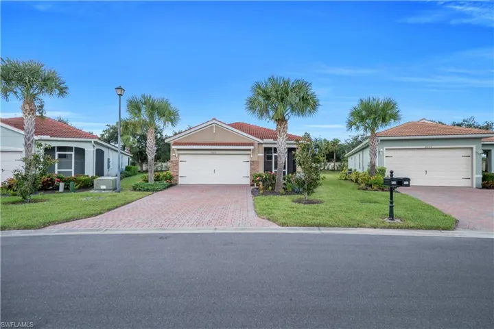 View of front facade featuring a tiled roof, a front lawn, stucco siding, and decorative driveway
