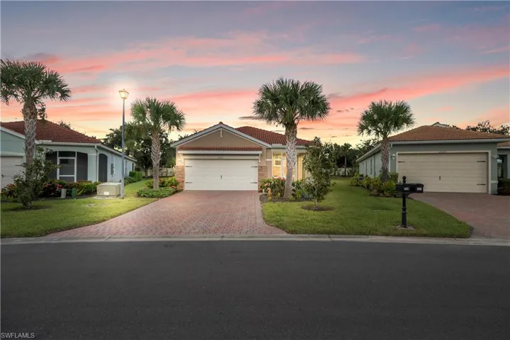 View of front of home featuring a tiled roof, a lawn, decorative driveway, and stucco siding