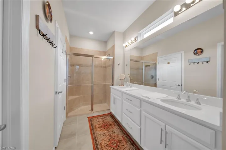 Full bathroom featuring a stall shower, double vanity, light tile patterned flooring, and recessed lighting