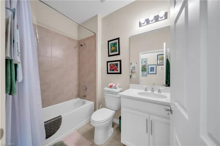 Full bath featuring shower / tub combo with curtain, vanity, and light tile patterned floors