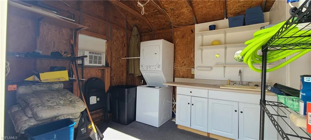 Laundry room featuring cooling unit, stacked washer / dryer, and sink