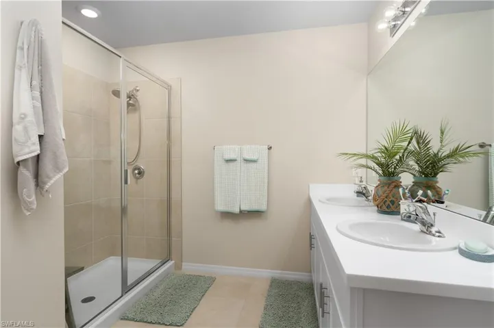 Bathroom with double vanity, a shower stall, recessed lighting, and light tile patterned floors