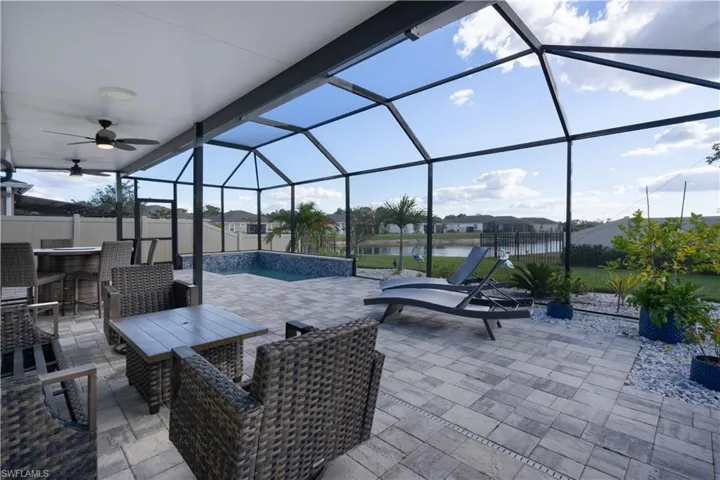 Fenced backyard with a sunroom, glass enclosure, a water view, an outdoor pool, and a patio