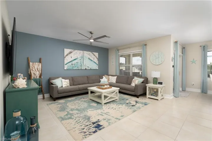 Living area featuring light tile patterned floors and a ceiling fan