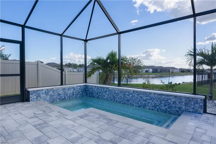 View of pool with a lanai, a sunroom, and a water view