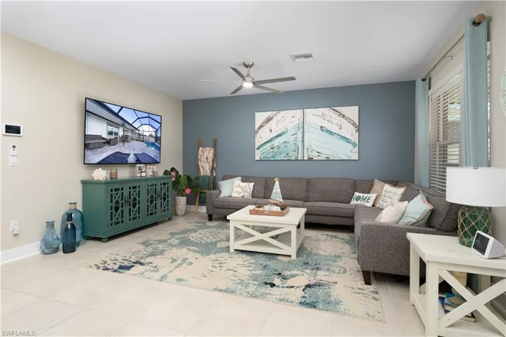 Tiled living area featuring a ceiling fan and baseboards