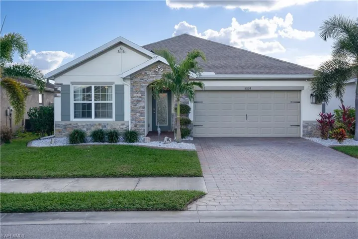 Ranch-style home featuring stone siding, decorative driveway, and stucco siding