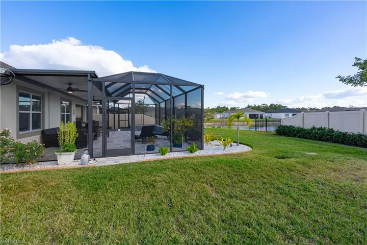 View of yard featuring ceiling fan, a patio, glass enclosure, a sunroom, and a water view