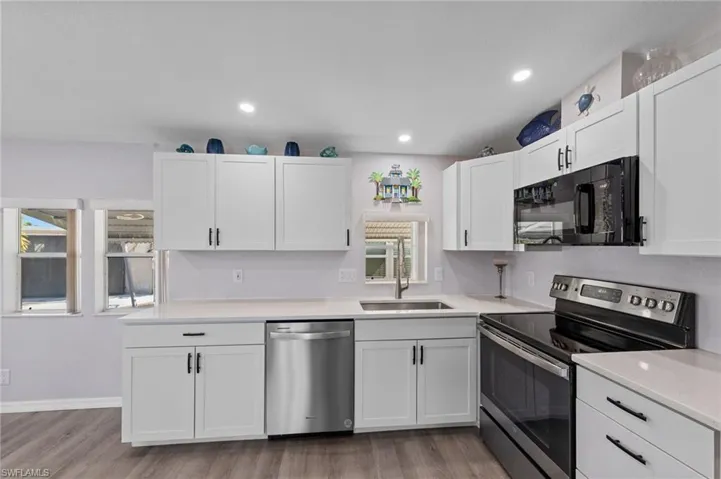 Kitchen with stainless steel appliances, white cabinets, light wood finished floors, and recessed lighting