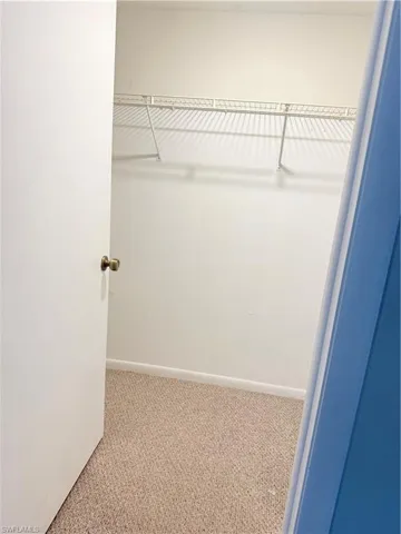 Carpeted closet space with a white wire shelving system and a brass door handle