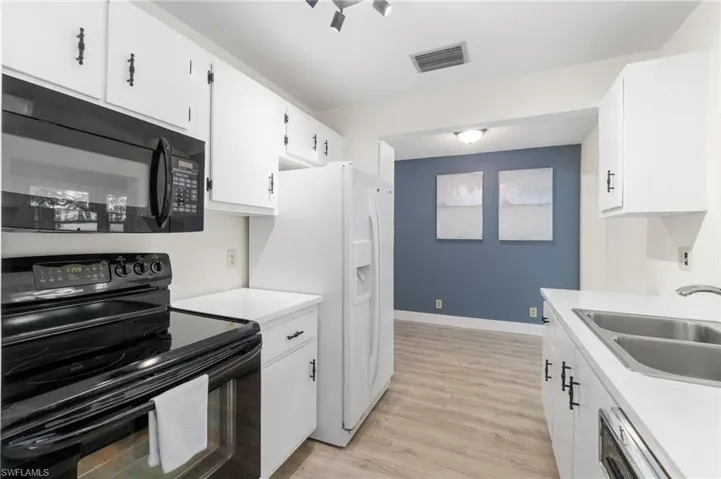 Kitchen with black appliances, light countertops, and white cabinetry