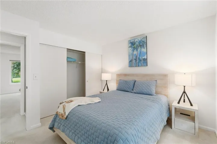 Bedroom with a closet, light carpet, and a textured ceiling
