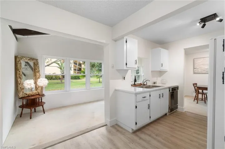 Kitchen featuring light countertops, white cabinets, freestanding refrigerator, plenty of natural light, and a textured ceiling
