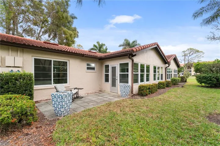 Rear view of house with a lawn, stucco siding, a tile roof, and a patio area