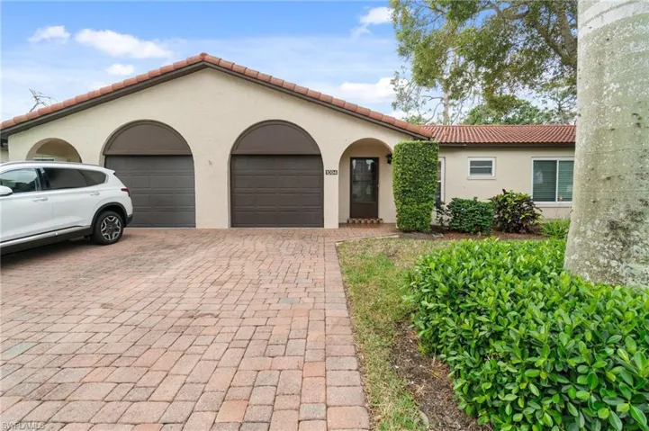 Mediterranean / spanish house with a garage, a tiled roof, decorative driveway, and stucco siding
