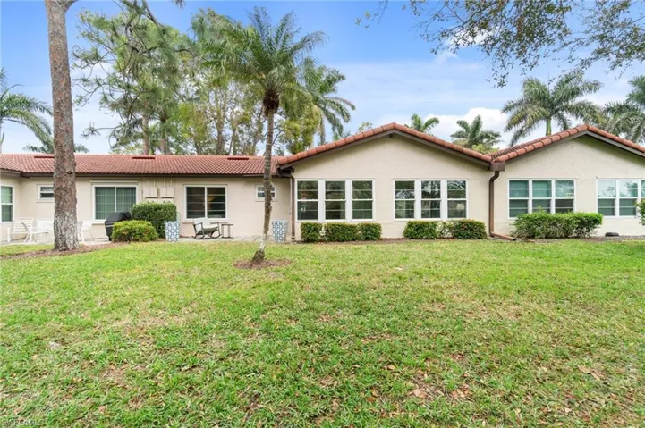 Back of house featuring a yard, a tile roof, and stucco siding