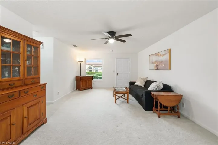 Living area featuring light carpet and a ceiling fan