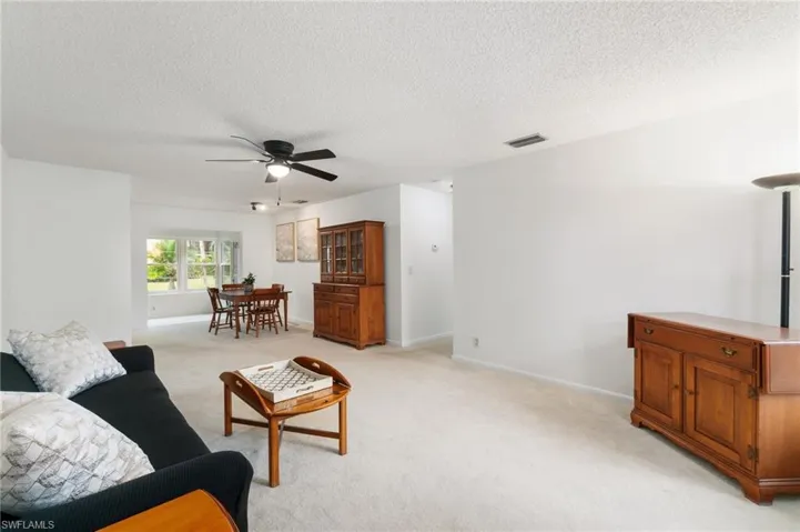 Living room featuring light carpet, a ceiling fan, and a textured ceiling