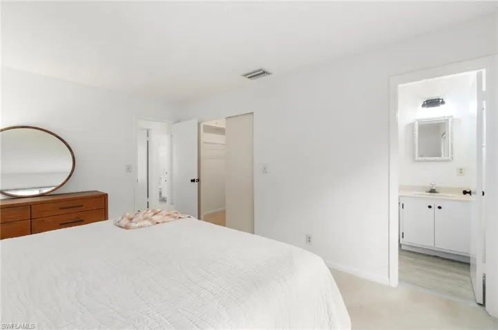Bedroom featuring ensuite bathroom, light colored carpet, and a spacious closet