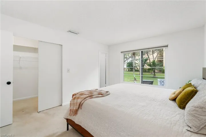 Bedroom with light colored carpet, a textured ceiling, and a spacious closet
