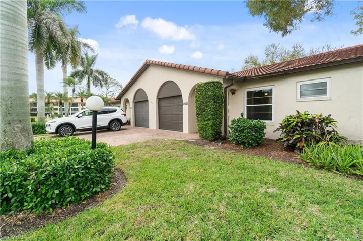 View of property exterior with a tiled roof, a garage, stucco siding, decorative driveway, and a lawn