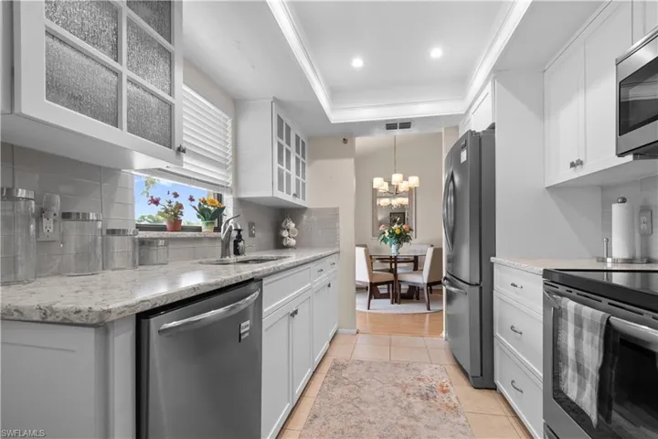 Kitchen featuring stainless steel appliances, white cabinets, and a tray ceiling