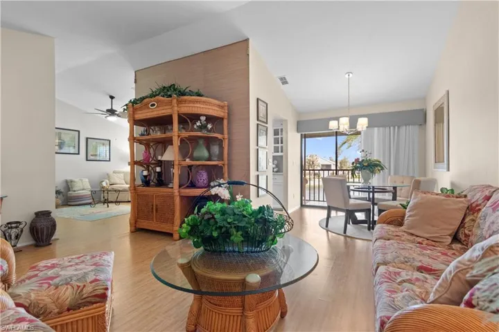 Living room with lofted ceiling, light wood-type flooring, a chandelier, and ceiling fan