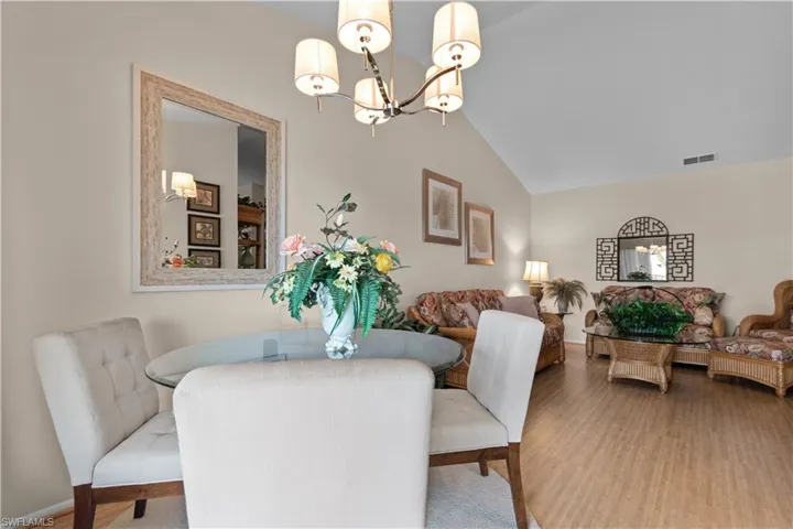 Dining room with wood finished floors, a chandelier, and lofted ceiling