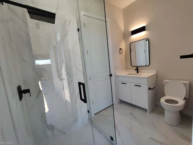 Full bathroom featuring a marble finish shower, vanity, and light marble finish flooring