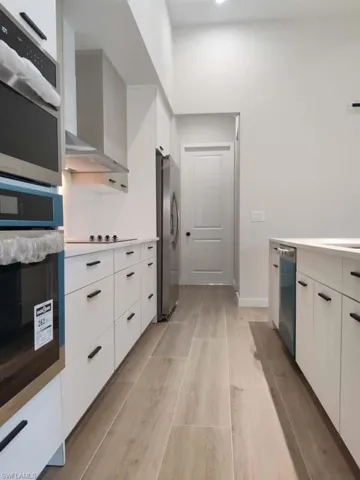 Kitchen with white cabinets, modern cabinets, light countertops, and light wood-type flooring